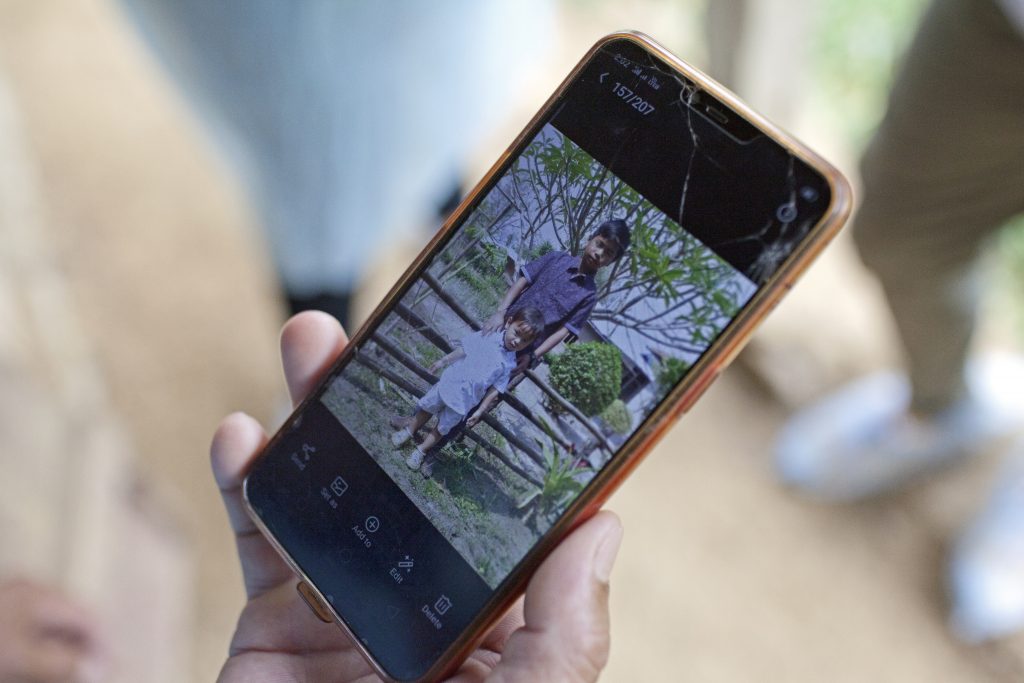 Nanjam Rajan Meitiei shares a photo of their two sons, aged 12 and 2, on his phone. The couple have had to leave their children in the care of a relative in order to self-isolate as per the strict directions of their village elders.  © Nikhil Roshan