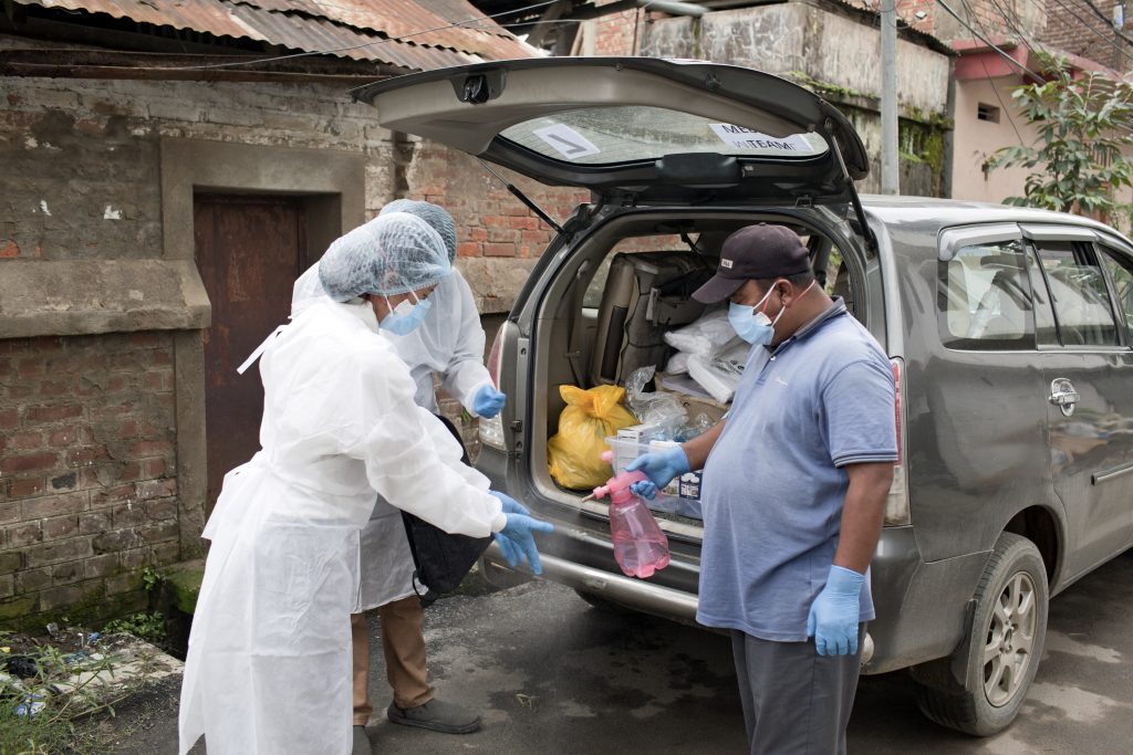 MSF staff put on PPE and use sanitizer before entering the home of a COVID-19 positive patient. © Nikhil Roshan